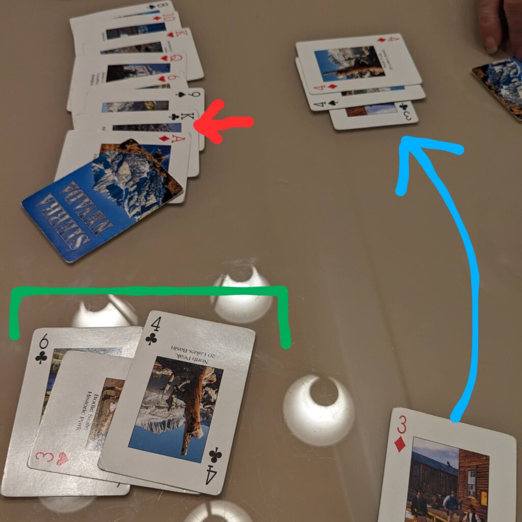 Image shows cards on the table, with a set of 4's in front of the other player and a run of clubs from 6 to 4 in front of the main player. A wild card has been played, and the main player has discarded and gone out.